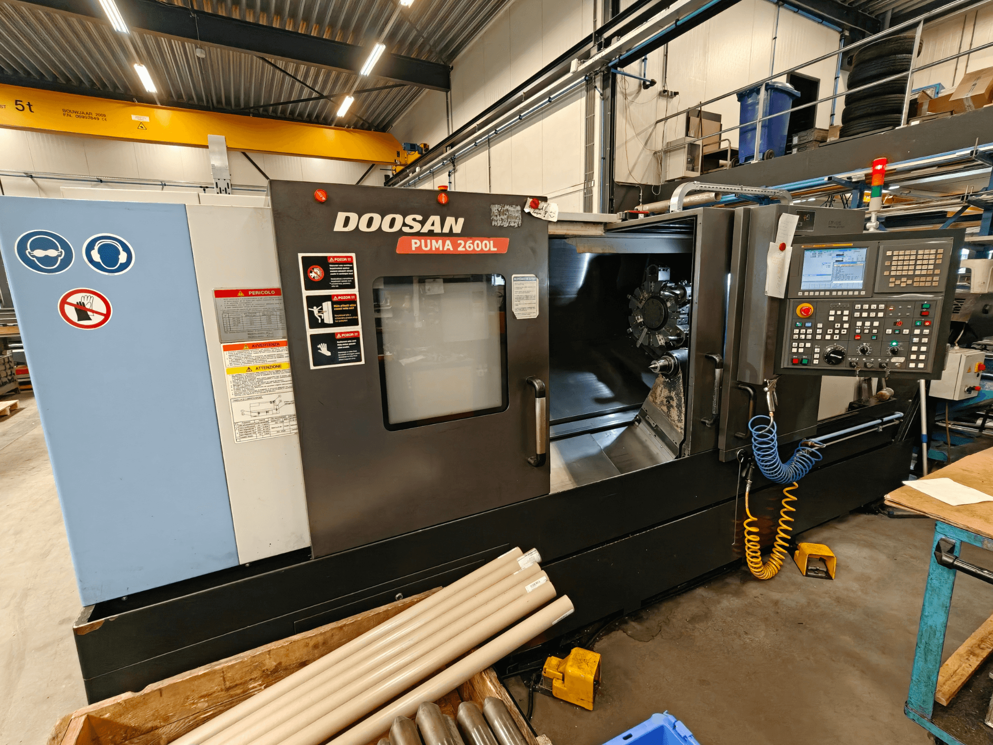 DOOSAN Puma 2600L horizontalios tekinimo staklės dirbtuvėse, šoninis vaizdas, kuriame matomas valdymo skydelis ir suklio sritis.