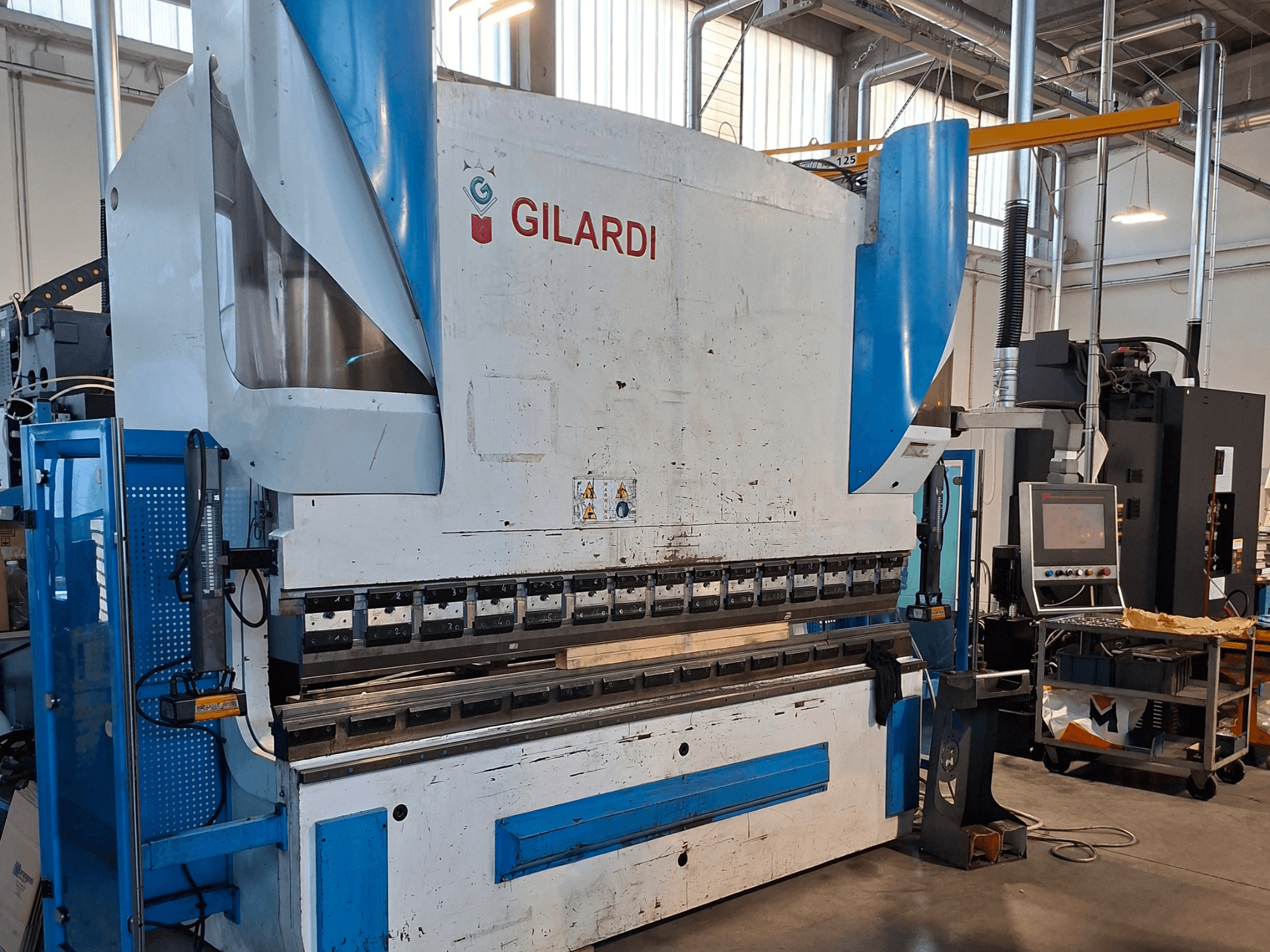 GILARDI (Italija) 3,25 hidraulinė presavimo mašina, vaizdas iš priekio, kuriame matomi valdymo elementai ir gamybos aplinkos detalės.