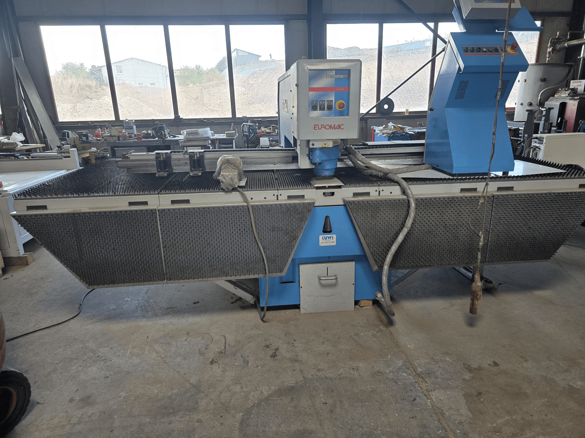 CNC štampavimo staklės „Euromac BX 1250/30“ dirbtuvėse, šoninis vaizdas, kuriame matomi įrankių valdymo elementai, pramoninis dizainas ir metalo pjovimo stalas.