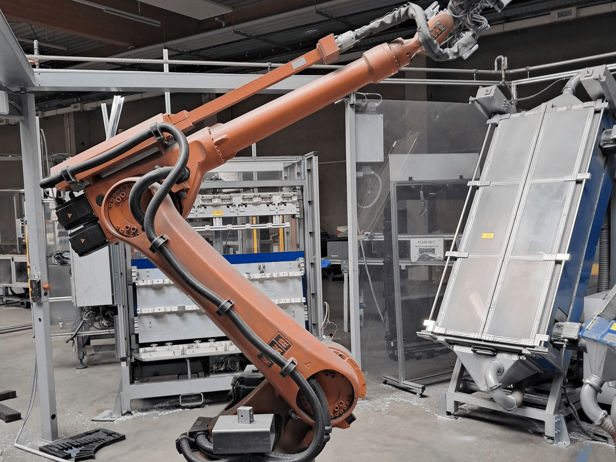 „KUKA KR 30L16-2“ roboto ranka gamykloje, šoninis vaizdas, kuriame matomi kabeliai ir mechaniniai komponentai.