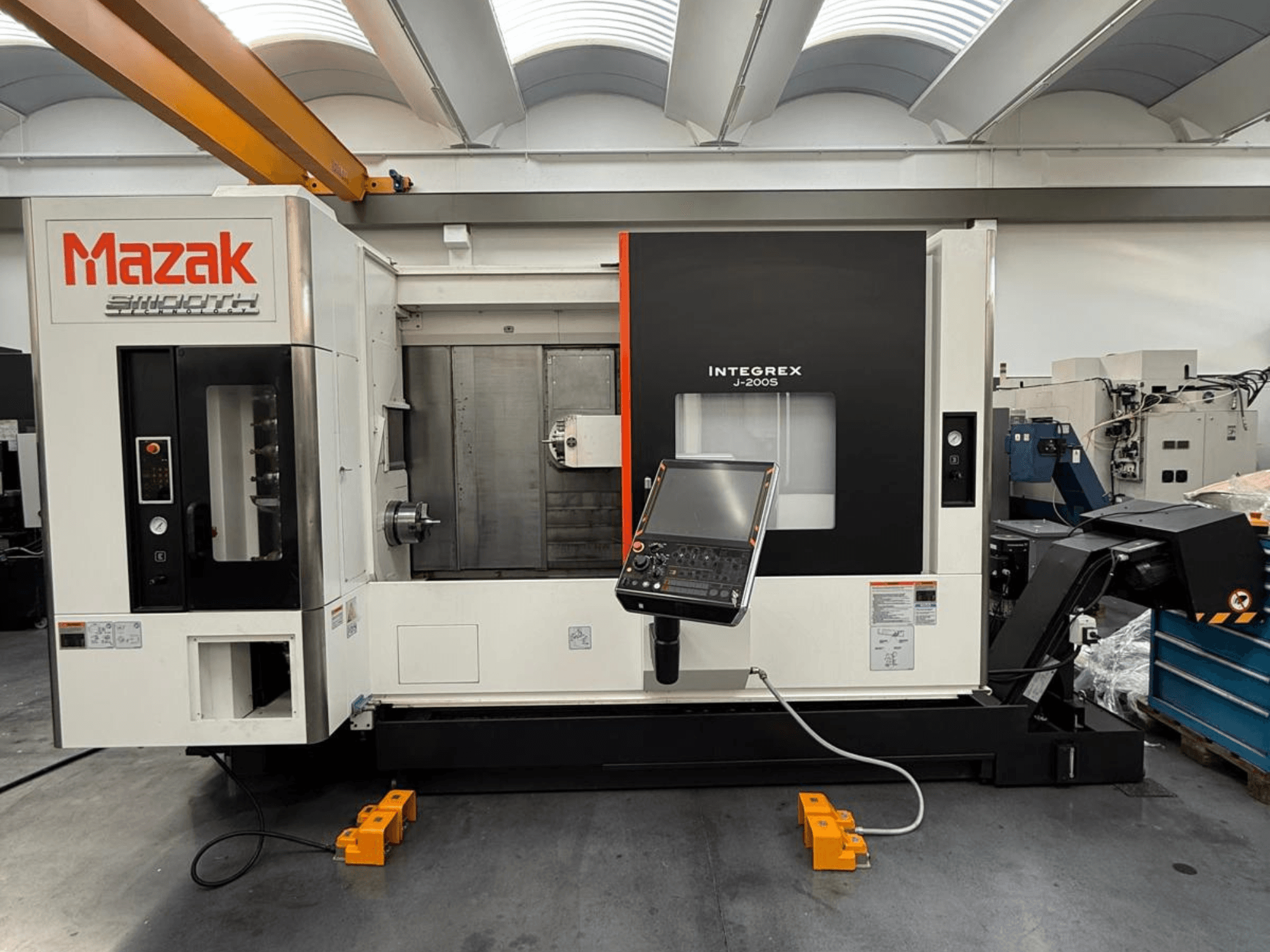 Mazak INTEGREX J-200 S frezavimo-apvirinimo centras iš priekio, su valdymo skydeliu ir apdirbimo zona, pastatytas ant gamyklos grindų.