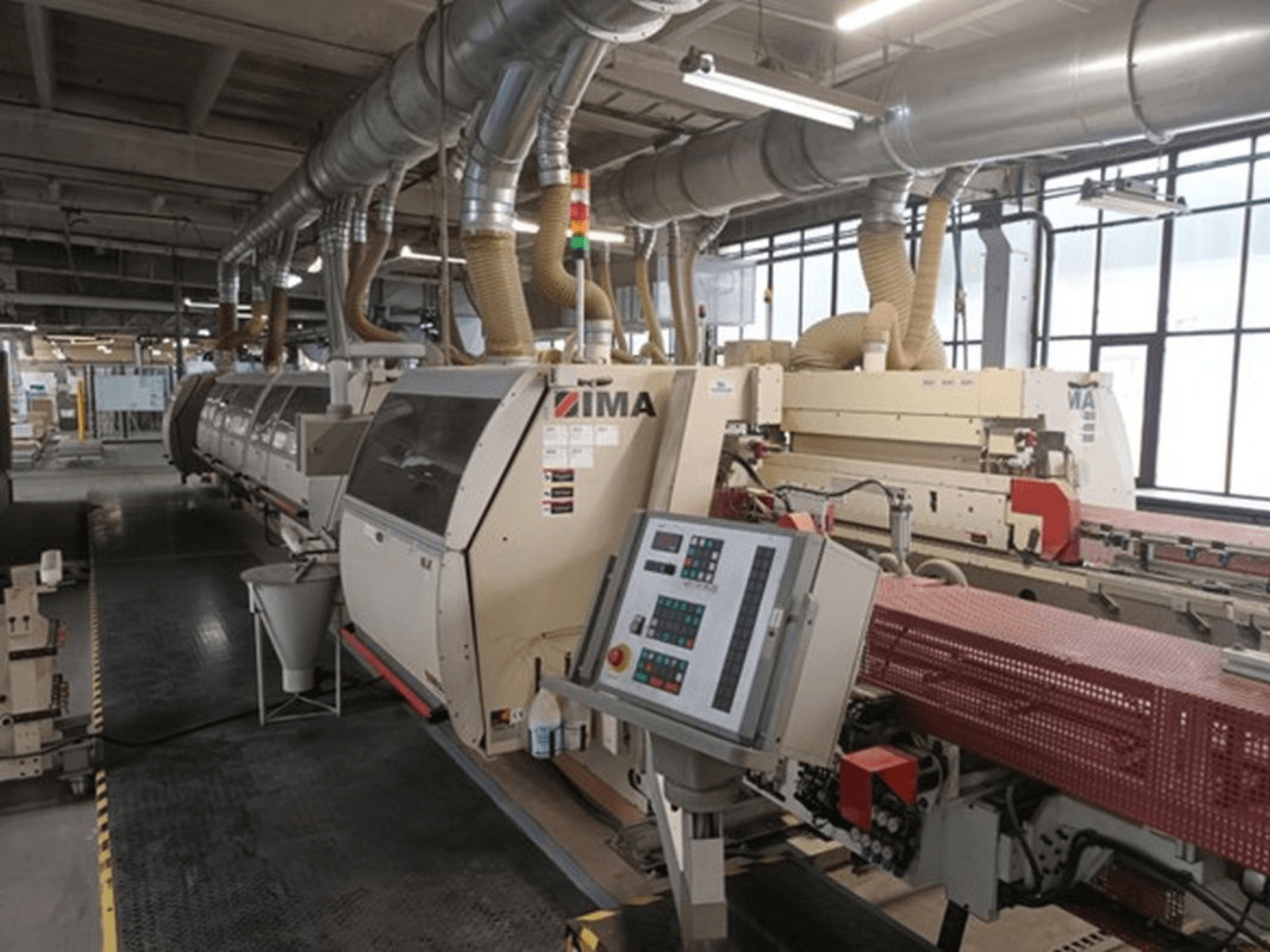 IMA pramoninės mašinos gamykloje, vaizdas iš priekio, valdymo skydai ir dulkių ištraukimo vamzdžiai.