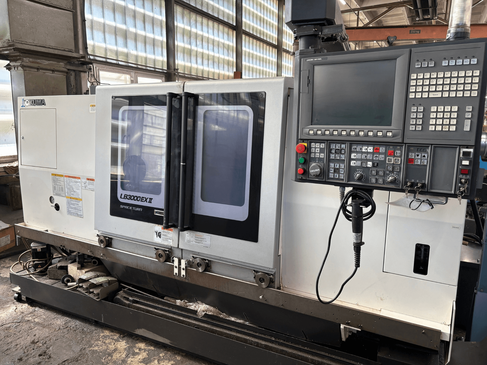 „Okuma LB3000EXII“ horizontalus tekinimo staklės, vaizdas iš priekio, kuriame matomas valdymo pultas ir pakrovimo durelės.