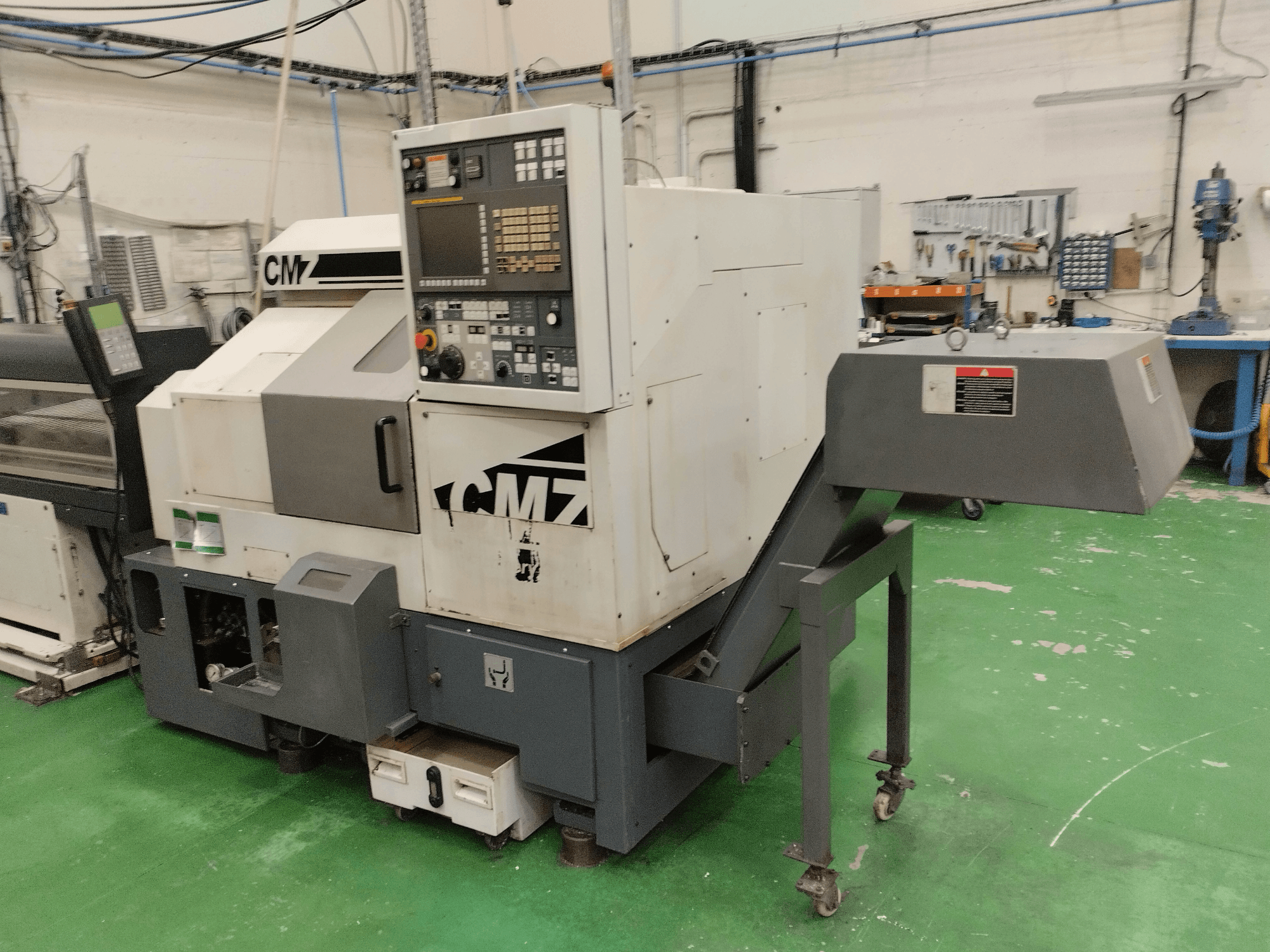 CMZ TB-67M tekinimo frezavimo centras iš priekio, su valdymo pultu ir padavimo mechanizmu, įrengtas dirbtuvių aplinkoje.