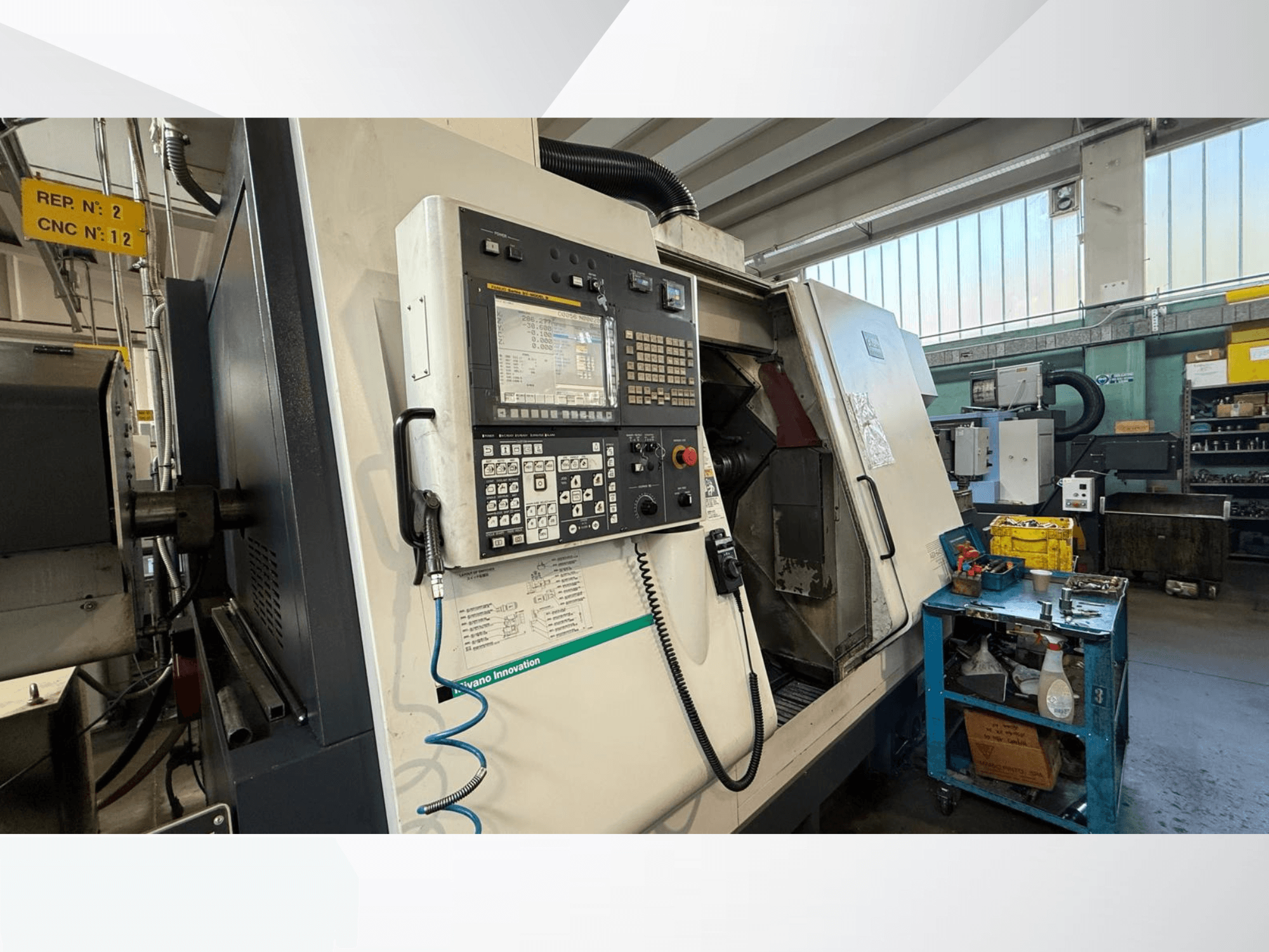 Horizontaliosios tekinimo staklės "Miyano ABX64 YY2" su valdymo skydeliu, įrankiais ir įranga dirbtuvėse, vaizdas iš priekio.