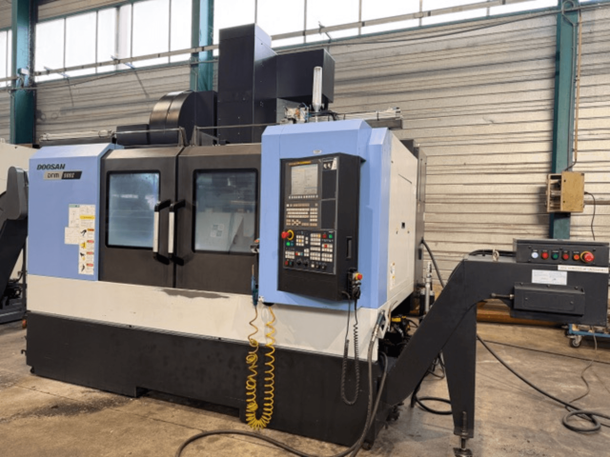 CNC frezavimo staklės "Doosan DNM 500II" su valdymo pultu ir įrankių laikikliu gamykloje, vaizdas iš priekio.