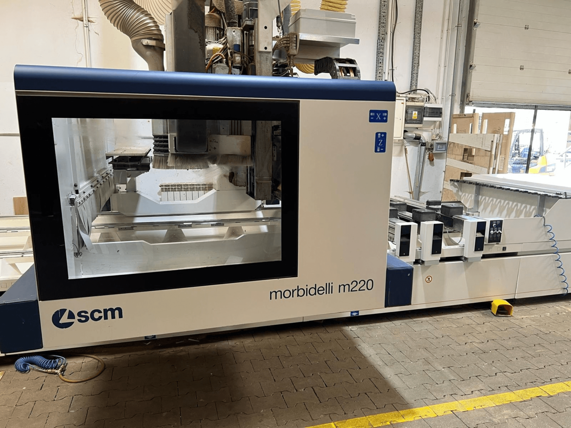 SCM Morbidelli M220 CNC apdirbimo centro vaizdas iš priekio, kuriame matomas didelis langas, valdymo pultas ir darbo zona.