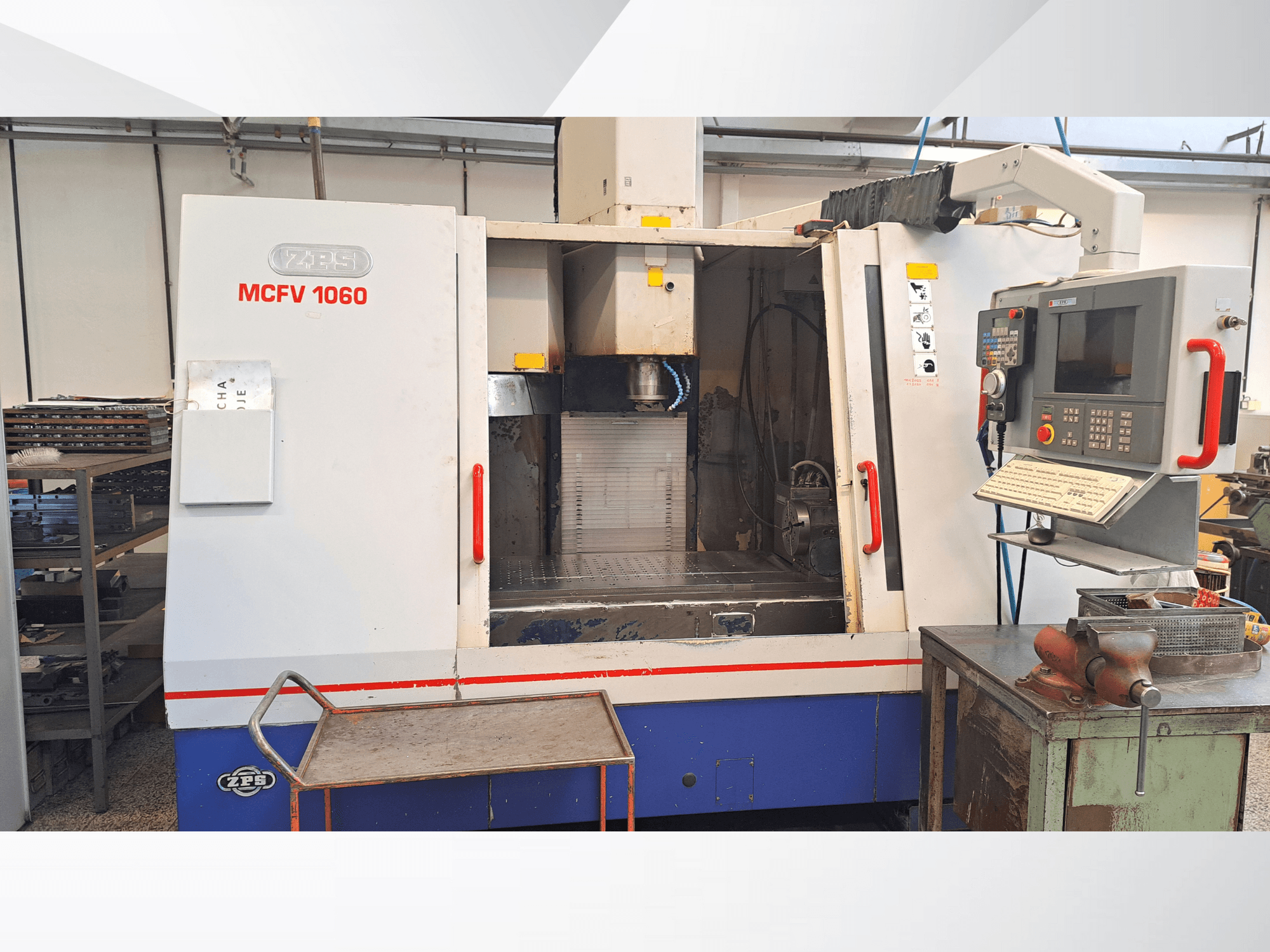 ZPS MCFV 1060 CNC staklės dirbtuvėse, priekinis vaizdas, kuriame matomas valdymo skydelis, suklys ir darbo zona; metalo pilkos ir mėlynos spalvos.