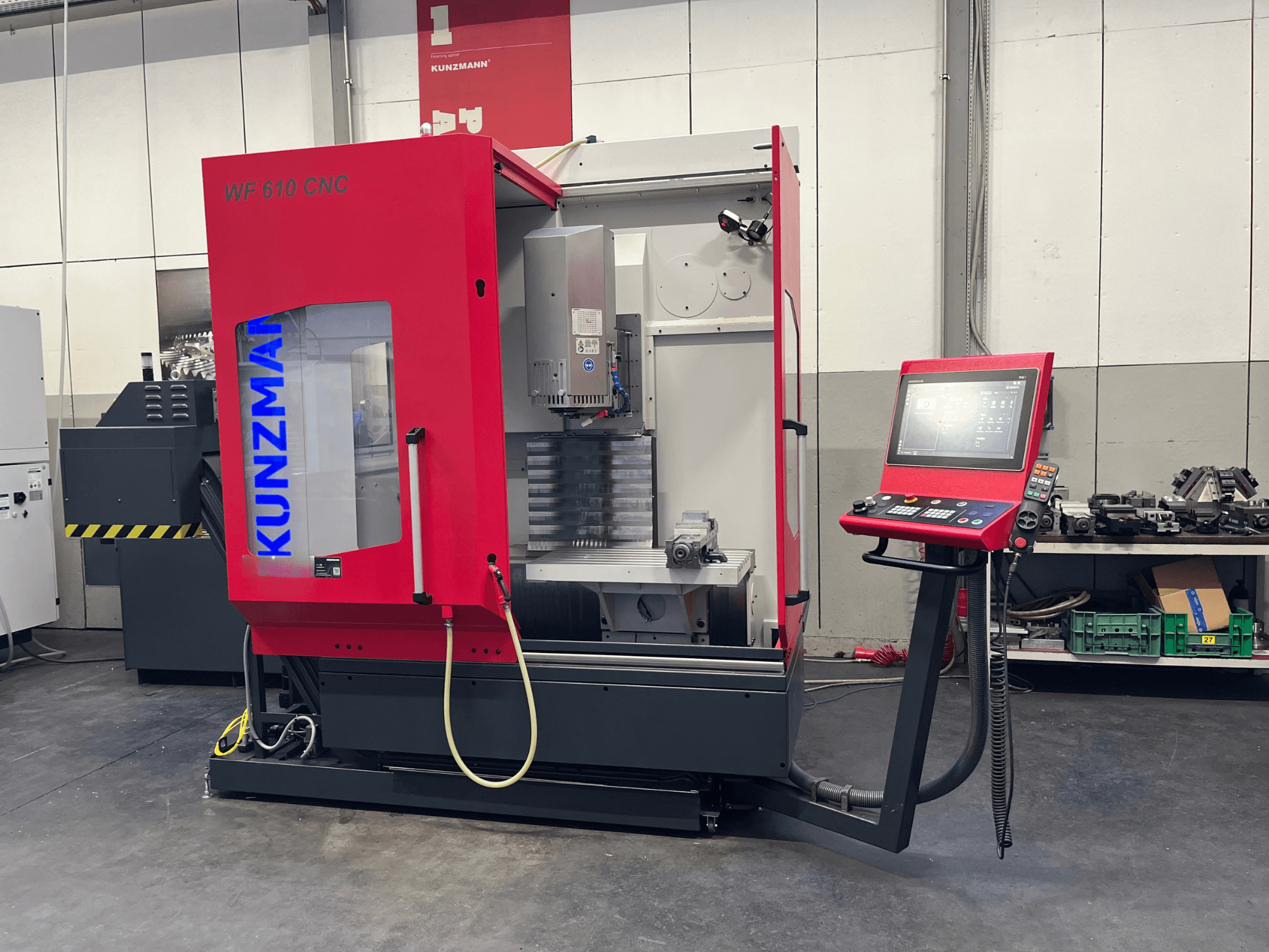 Dirbtuvėse esantis vertikalusis apdirbimo centras „KUNZMANN WF 610 CNC“, kuriame matomas valdymo pultas ir staklių komponentai.