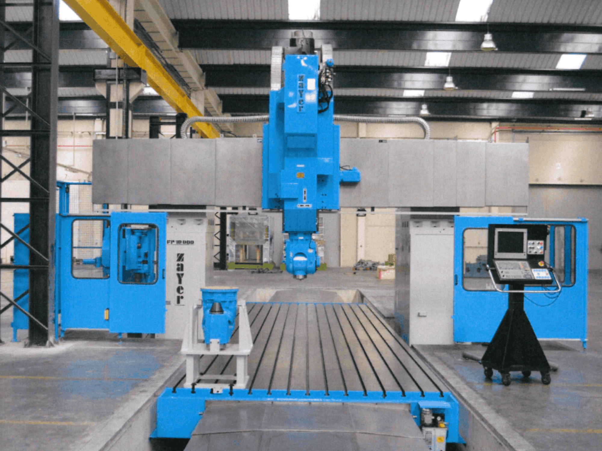 „Zayer FP-10000“ lovinio tipo frezavimo staklių vaizdas iš priekio, kuriame matoma mėlyna konstrukcija, valdymo pultas ir tikslieji komponentai.