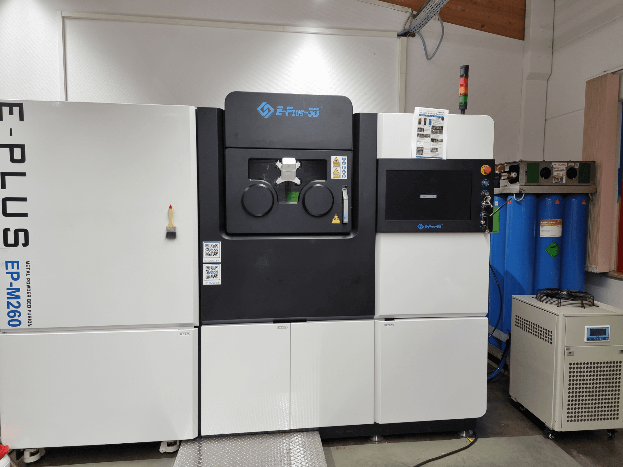 „Eplus3D EP-M260“ metalo 3D spausdintuvo vaizdas iš priekio, kuriame matomos dvi kameros ir valdymo skydelio detalės.