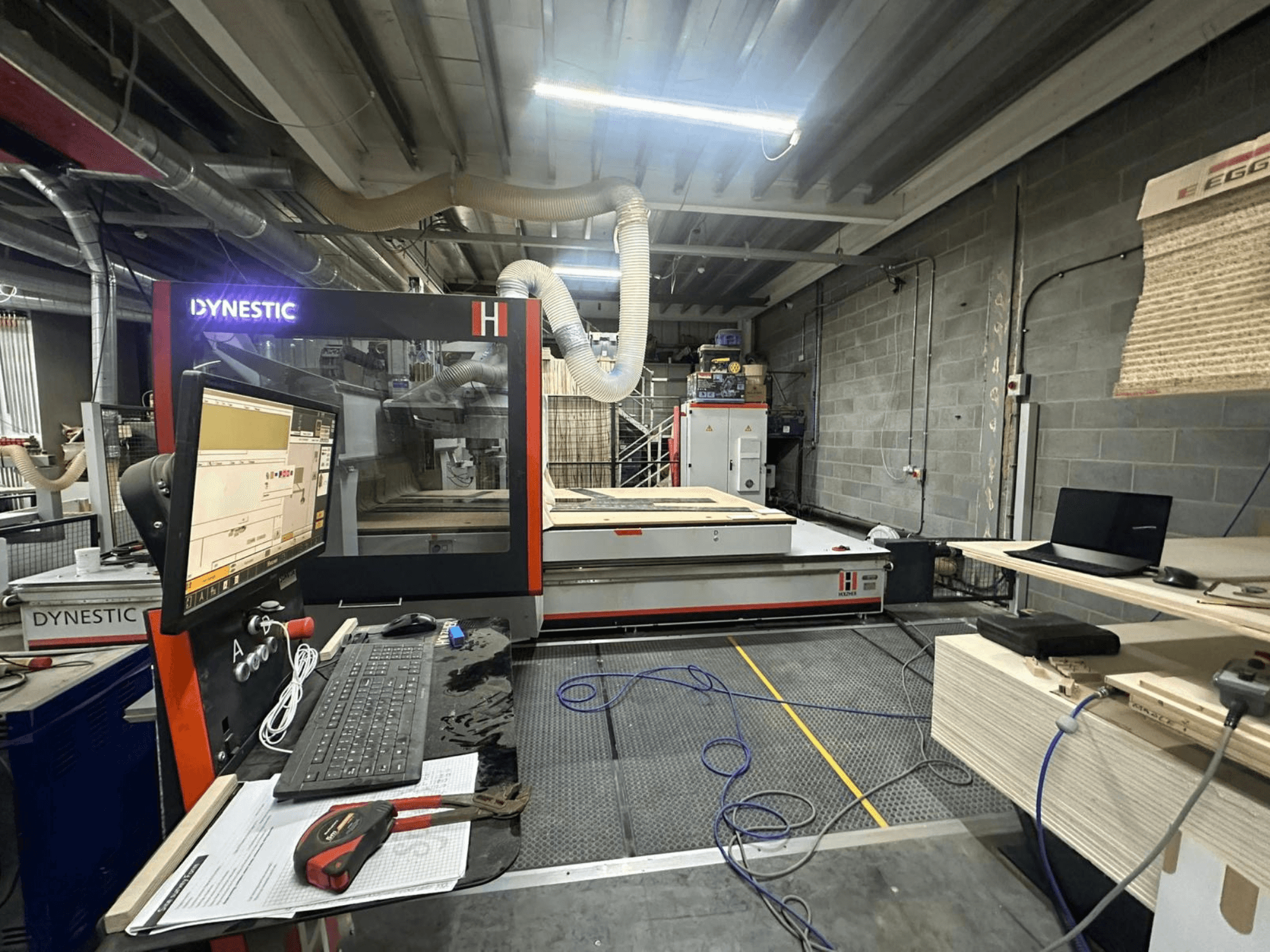 Medienos apdirbimo staklės HOLZHER Dynestic 7535 dirbtuvėse, matomas valdymo skydelis, monitorius ir medžiagos ant darbo stalo, vaizdas iš priekio.