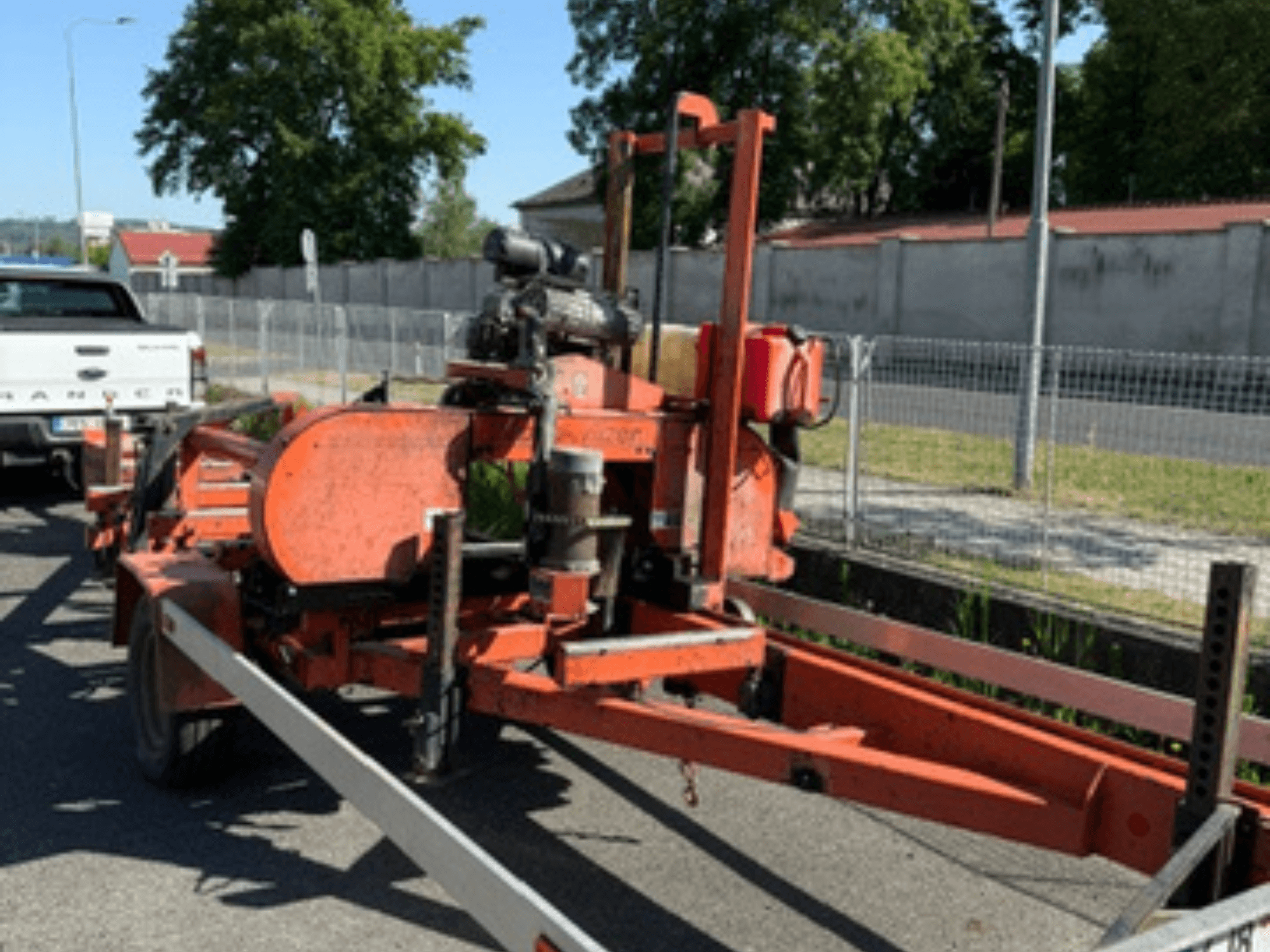 WOOD-MIZER LT40 medienos juostinė pjūklė, oranžinės spalvos, vaizdas iš šono ant priekabos, matomi ratai ir variklio komponentai.