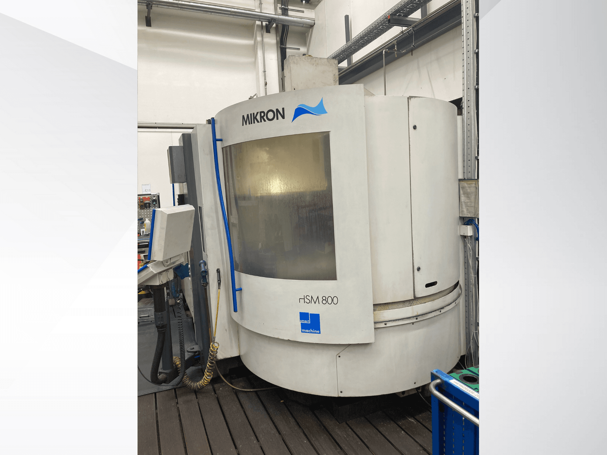 "Mikron rISM 800 CNC" staklės, vaizdas iš priekio su valdymo skydeliu, cilindro formos konstrukcija ir mėlynais akcentais, įrengtos dirbtuvių aplinkoje.