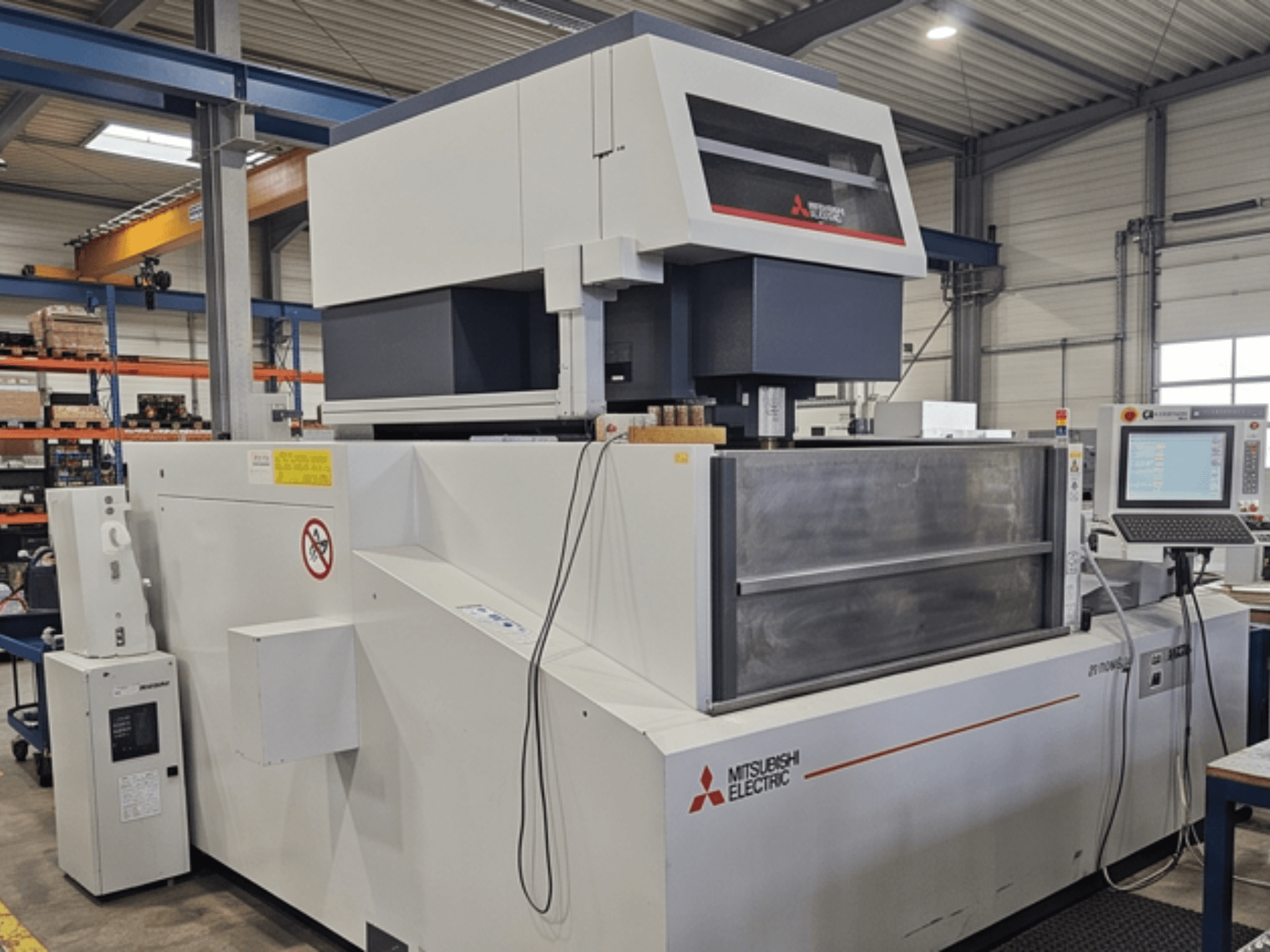 „Mitsubishi MV-4800“ vielos elektroerozijos staklės, vaizdas iš priekio, kuriame matomas valdymo skydas ir darbo zona gamyklos aplinkoje.