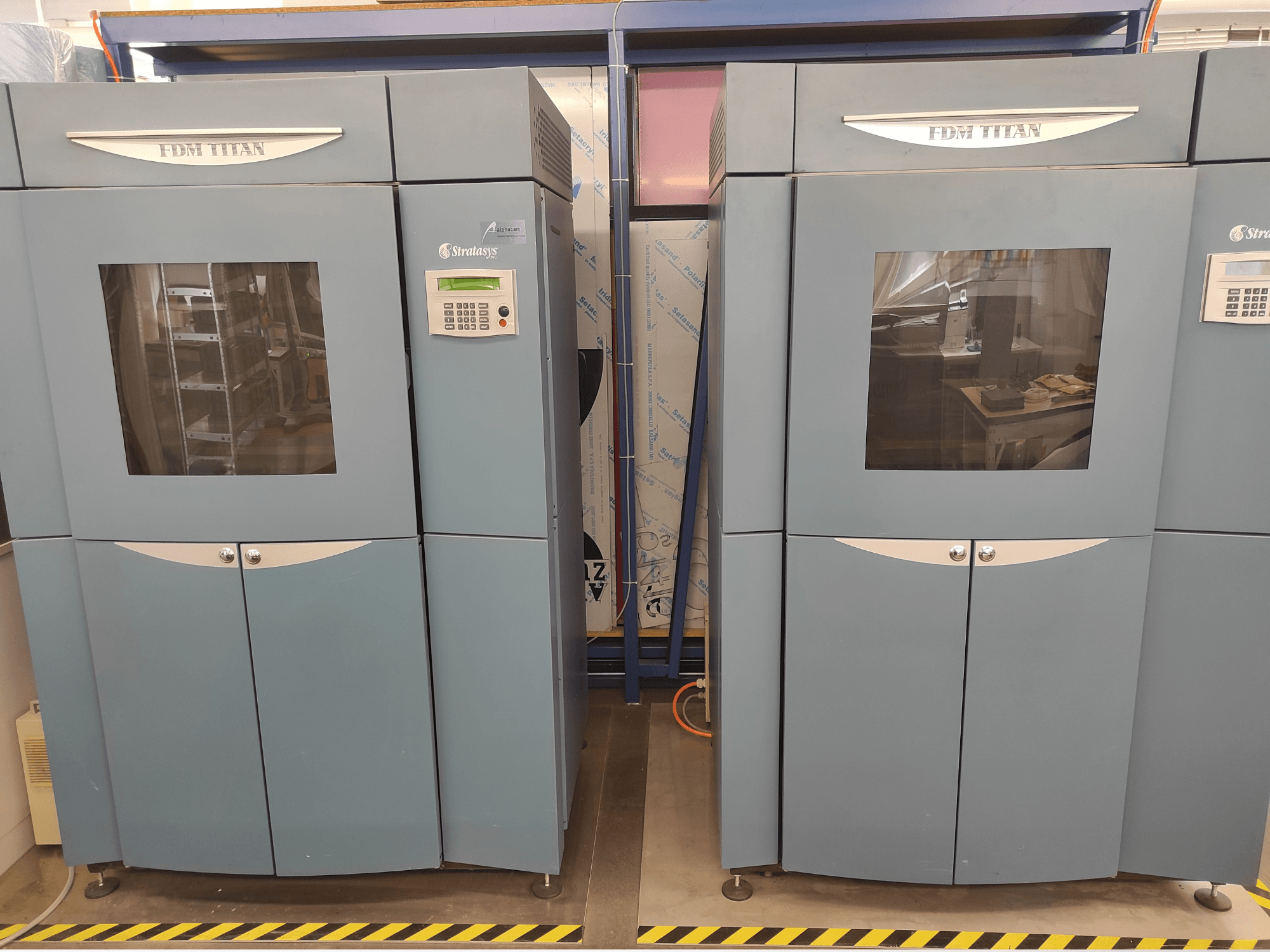 „Stratasys FDM TitanTI T0031“ plastikinio 3D spausdintuvo vaizdas iš priekio; matomas valdymo skydelis ir skaidrus langelis.