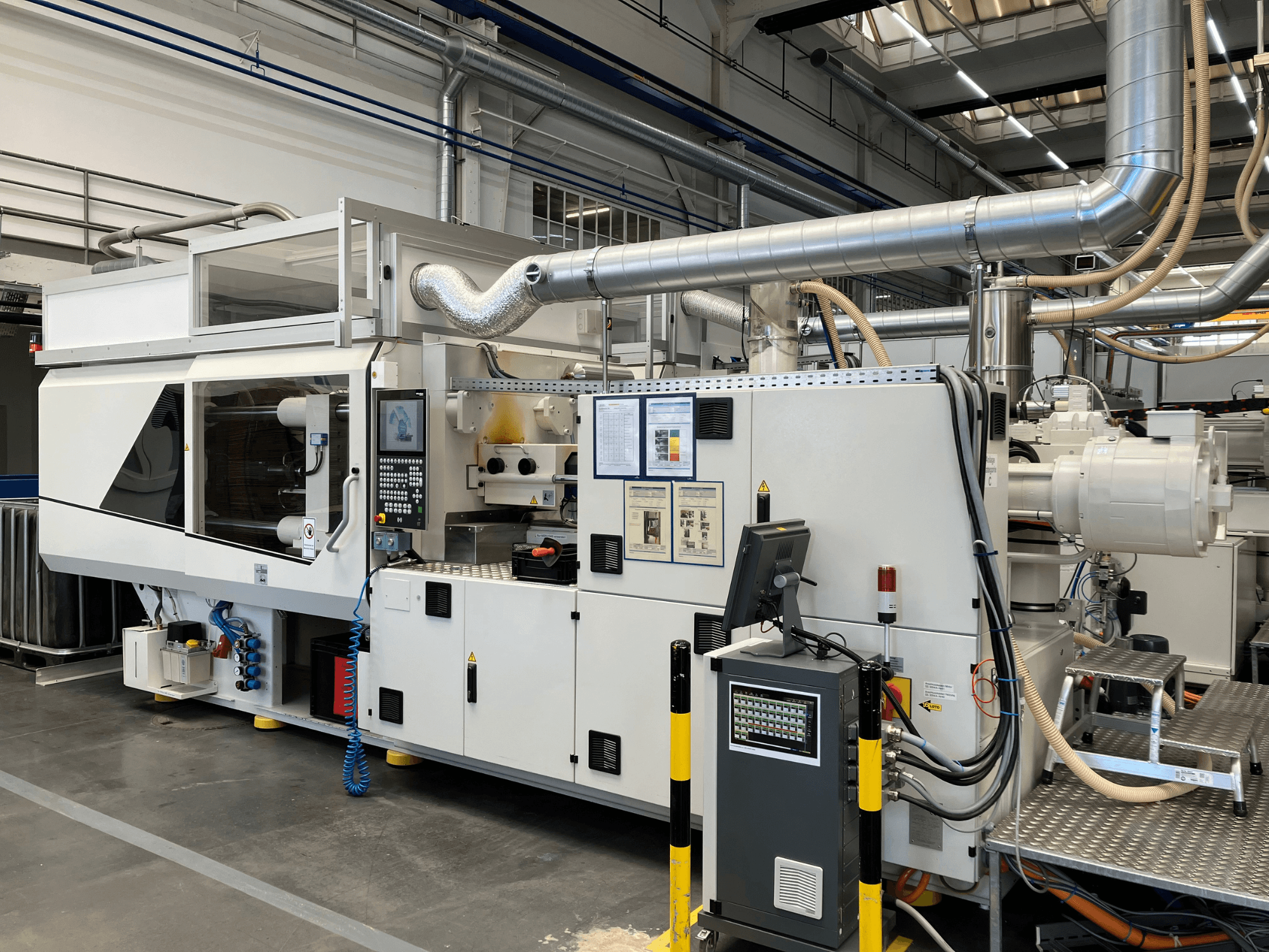 Pramoninės mašinos su valdymo skydeliu, vamzdžiais ir ekranais, pasižyminčios elegantišku baltu dizainu ir techninėmis detalėmis, vaizdas iš priekio.