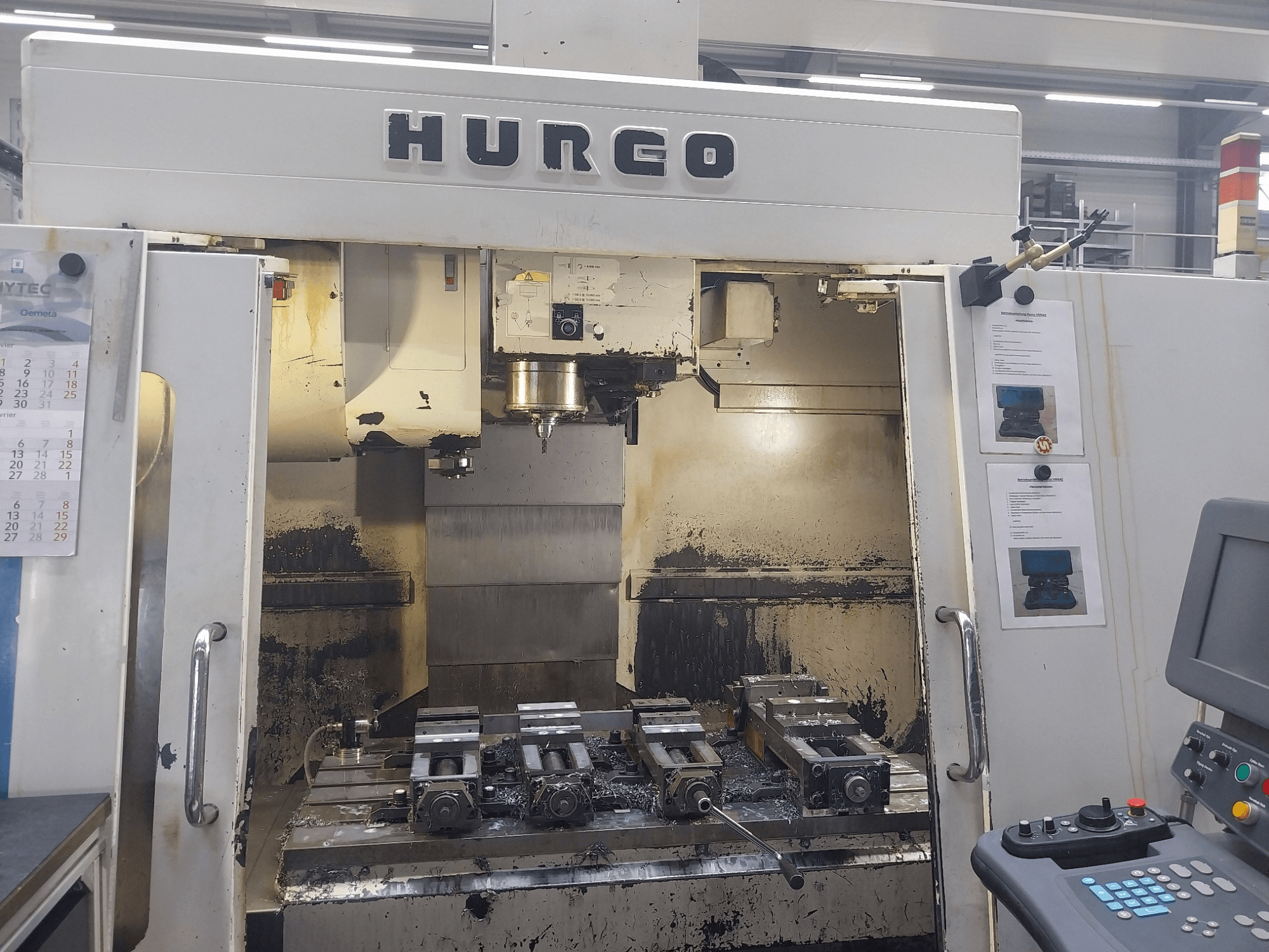 Hurco VMX 42 vertikalusis apdirbimo centras, vaizdas iš priekio, matomas darbo stalas su armatūra ir valdymo skydelis, šiek tiek nusidėvėjęs.