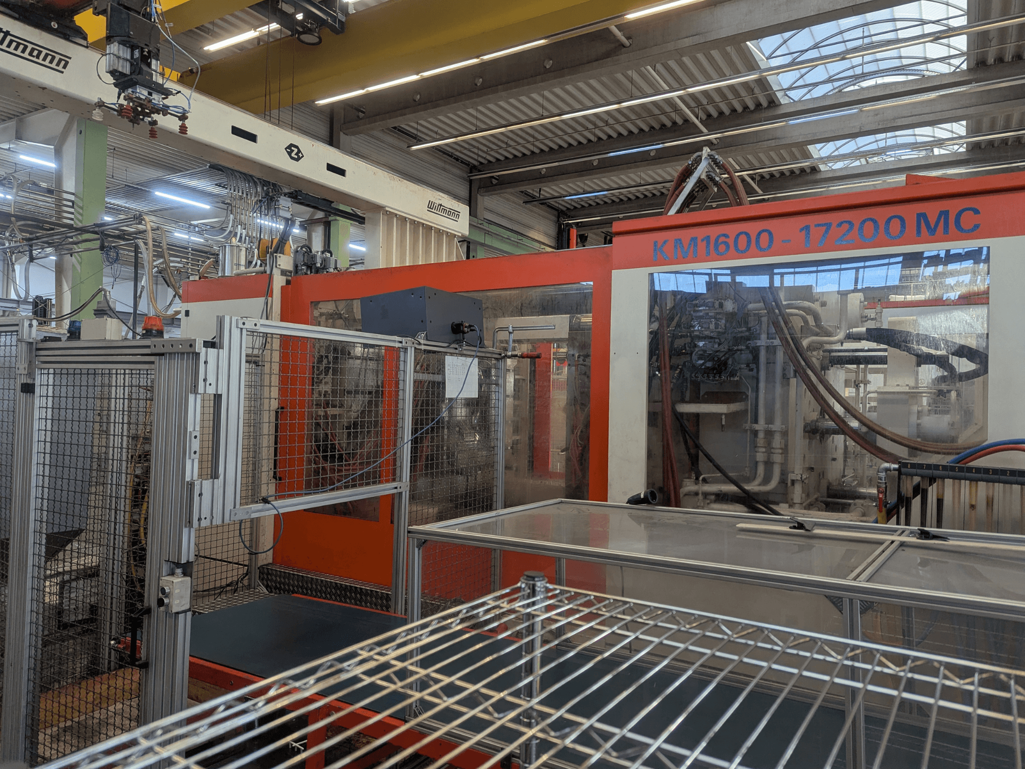 Hidraulinė liejimo mašina Krauss Maffei KM 1600-17200MC, priekinis vaizdas su matomu valdymo skydeliu ir hidraulinėmis linijomis.