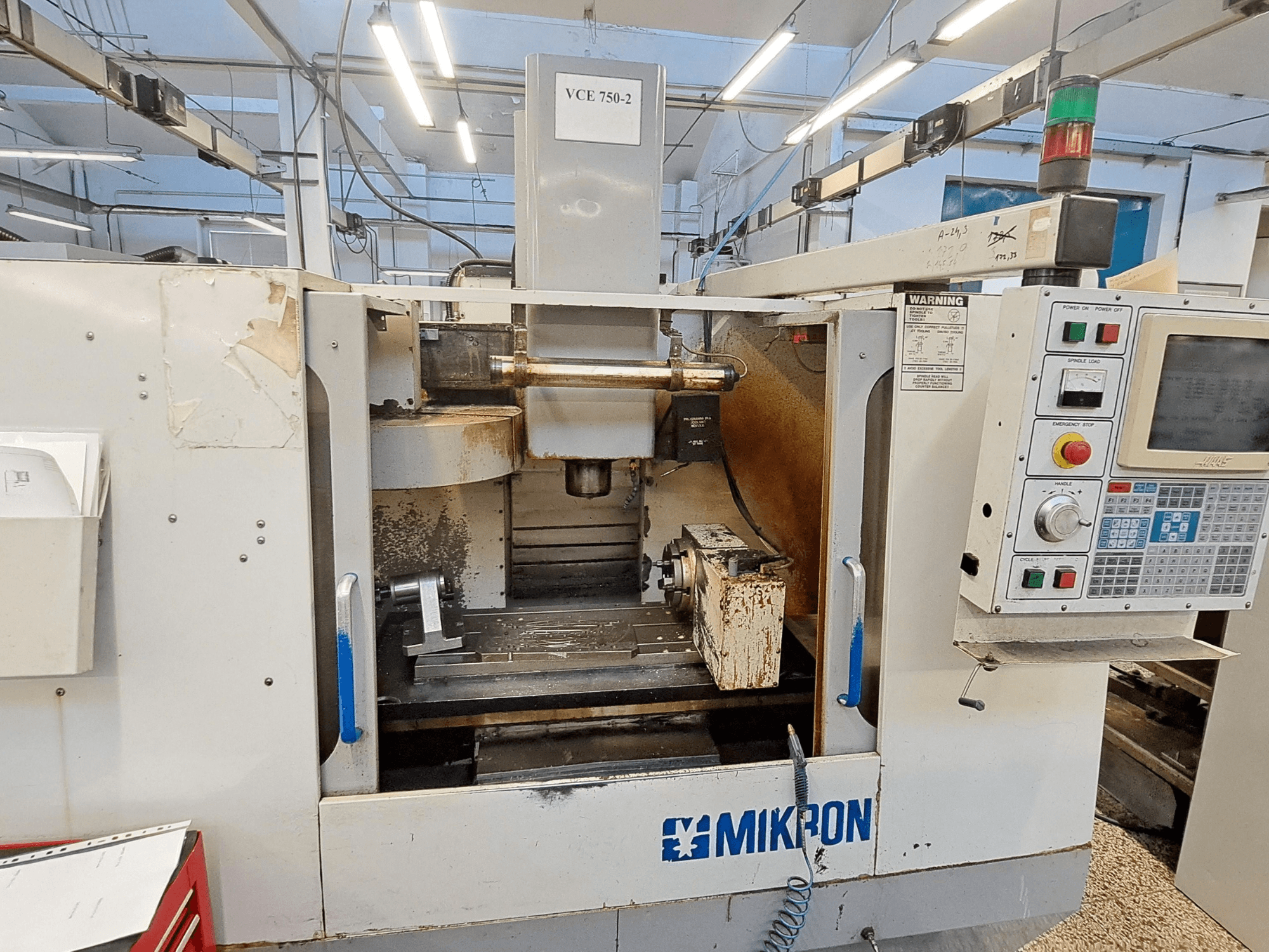 Mikron VCE 750-2 CNC frezavimo staklės, vaizdas iš priekio, valdymo skydelis ir suklys apdirbimo zonoje, matomas nusidėvėjimas ir nešvarumai.