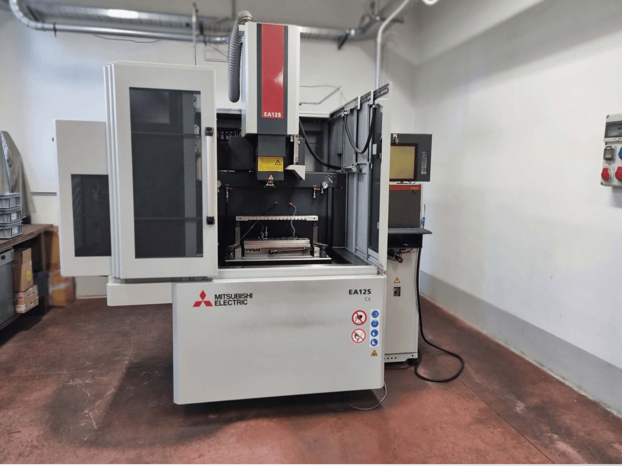 "Mitsubishi Electric EA12S" vielos pjovimo staklės, vaizdas iš priekio, atviros durelės, valdymo skydelis ir saugos etiketės.