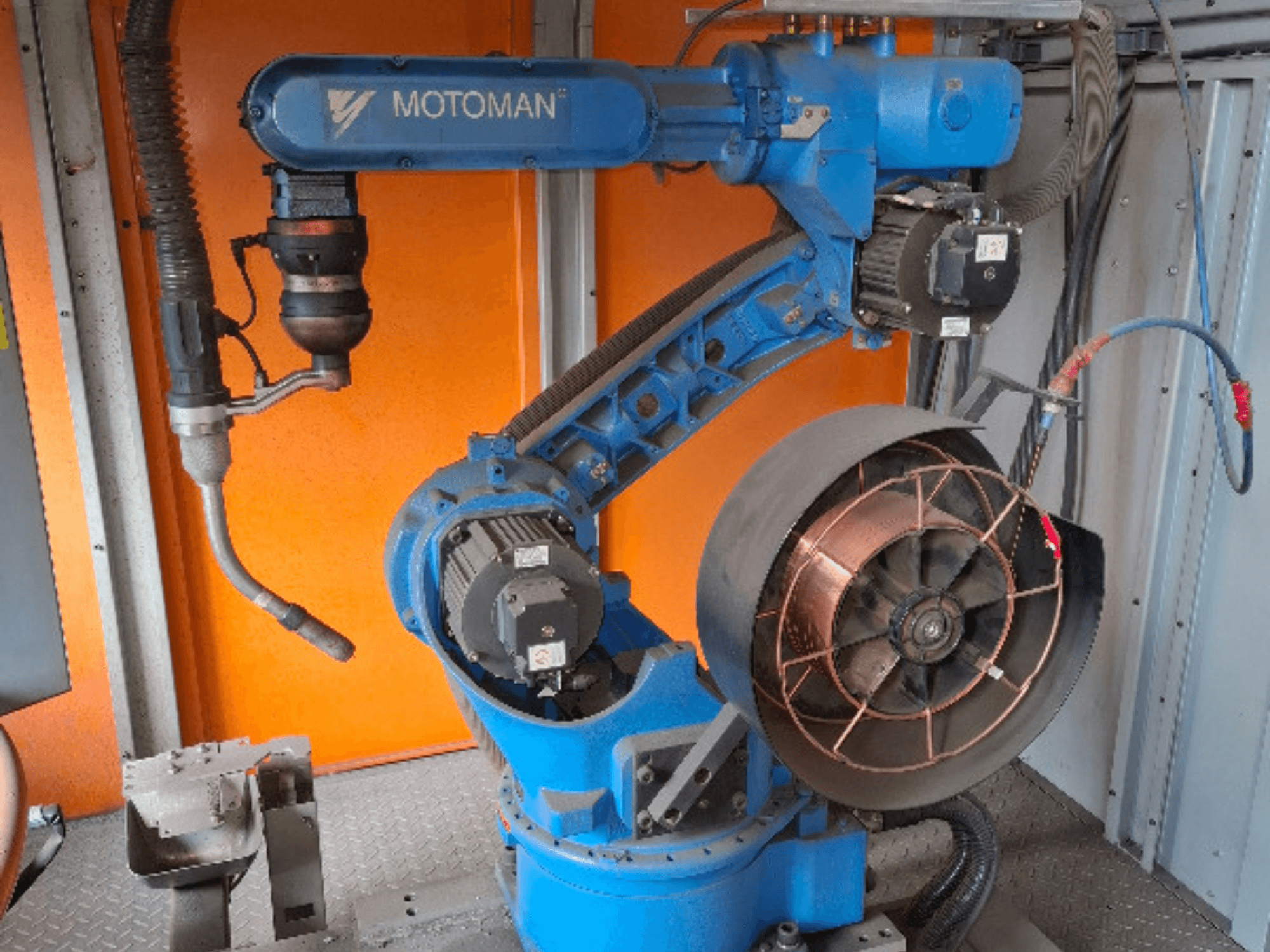 Mėlynos spalvos MOTOMAN roboto ranka su pritvirtintu ventiliatoriumi ir įrankiais, šoninis vaizdas, matomos mechaninės detalės ir jungtys.