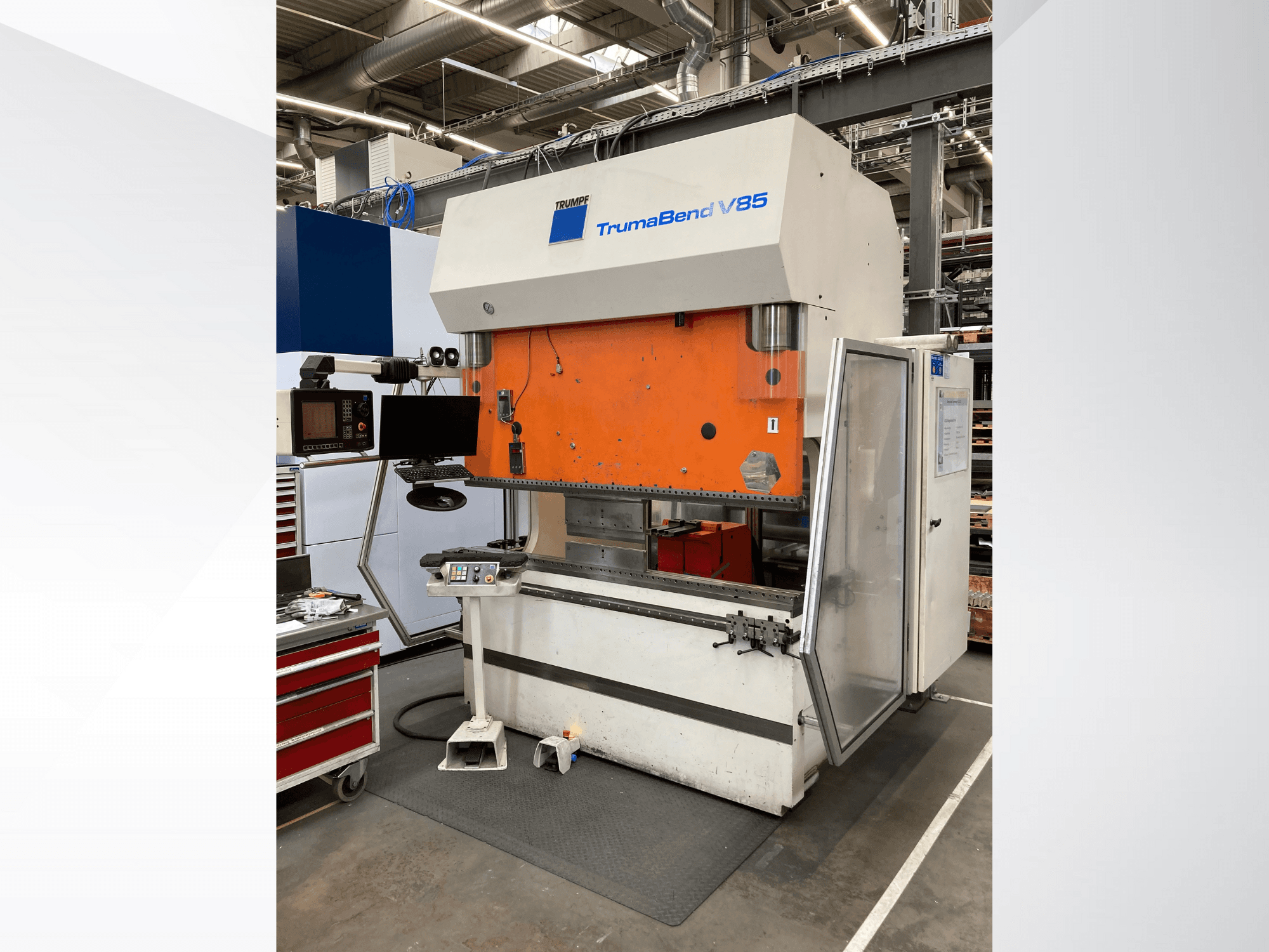 Gamyklinės lenkimo staklės "TruMatic V85" su oranžiniu priekiniu skydeliu, valdymo ekranu ir atidarytomis šoninėmis durelėmis, vaizdas iš šono.