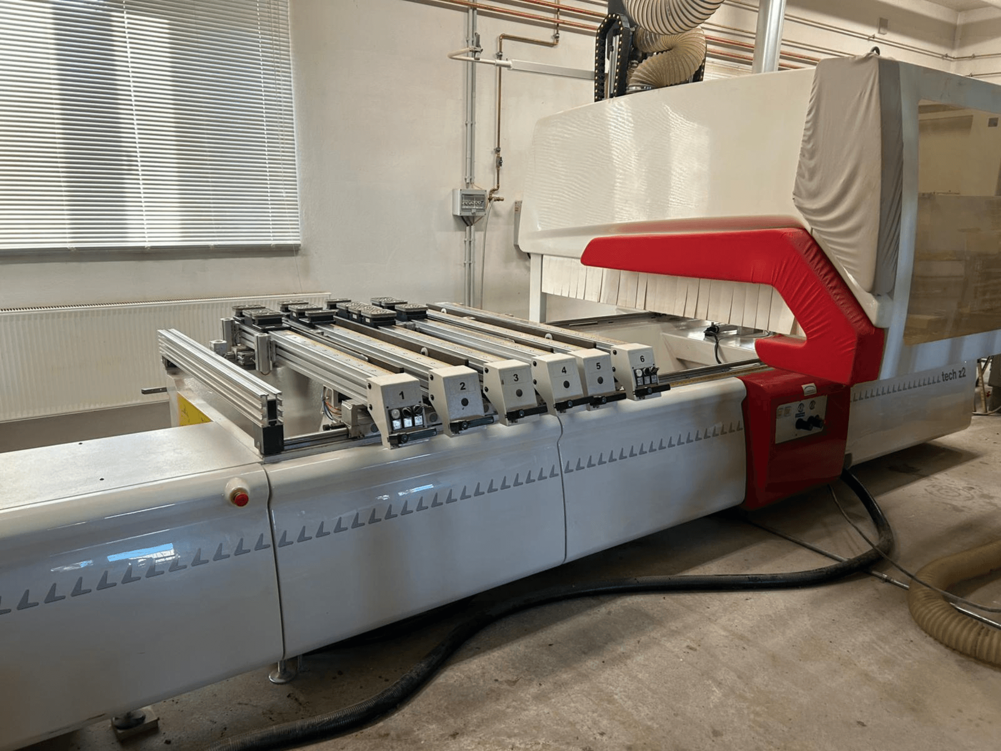 SCM TECH Z2-27-C medienos gręžimo staklės, šoninis vaizdas, kuriame matomas valdymo skydelis ir bėgiai, su raudonos ir baltos spalvos dizaino elementais.