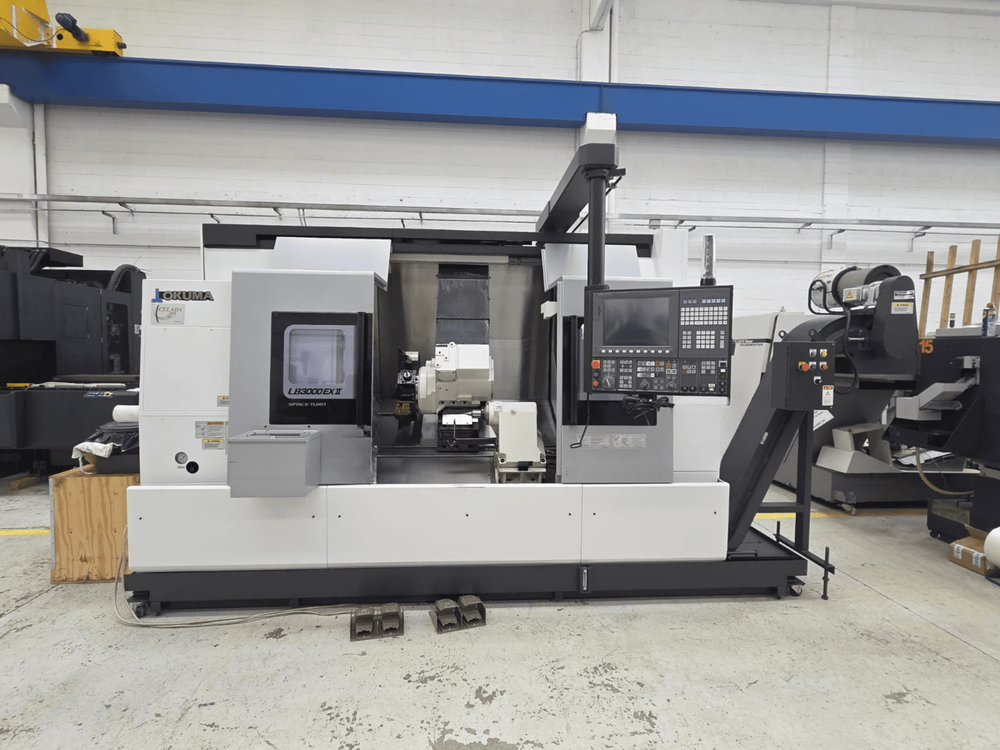 Okuma LB 3000 EXII horizontalios tekinimo staklės, parodytos iš priekio, su valdymo skydeliu ir įrankių laikikliu.